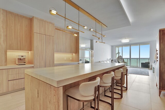 704 N Ocean Blvd Unit 602, Pompano Beach, FL 33062 - kitchen featuring light brown cabinets, open floor plan, modern cabinets, expansive windows, and a breakfast bar