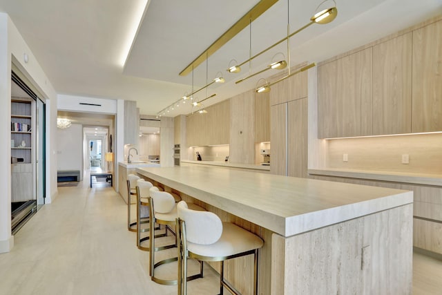 kitchen with pendant lighting, light brown cabinets, a kitchen bar, and a center island