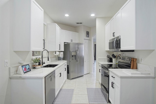 kitchen featuring light tile patterned floors, white cabinets, stainless steel appliances, and sink