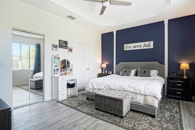 bedroom with ceiling fan, hardwood / wood-style flooring, and a raised ceiling