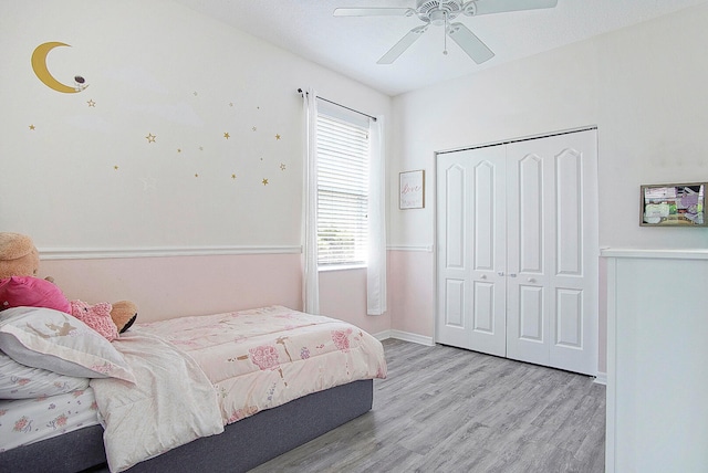 bedroom with light wood-type flooring, ceiling fan, and a closet