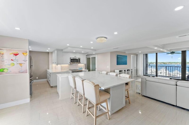 kitchen featuring white cabinets, a kitchen breakfast bar, a water view, appliances with stainless steel finishes, and a kitchen island