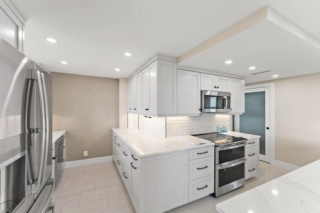 kitchen with tasteful backsplash, light stone countertops, white cabinets, and appliances with stainless steel finishes