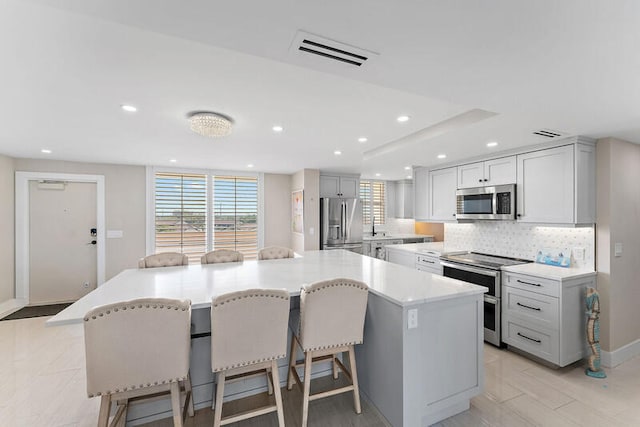 kitchen with appliances with stainless steel finishes, a center island, a kitchen breakfast bar, and backsplash