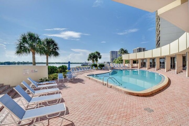 view of swimming pool with a patio and a water view