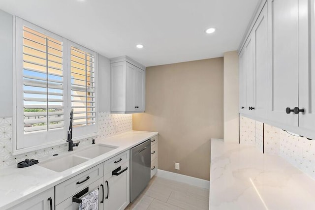 kitchen with light stone countertops, tasteful backsplash, stainless steel dishwasher, and sink