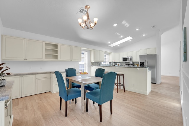 dining area featuring an inviting chandelier, lofted ceiling, and light hardwood / wood-style floors