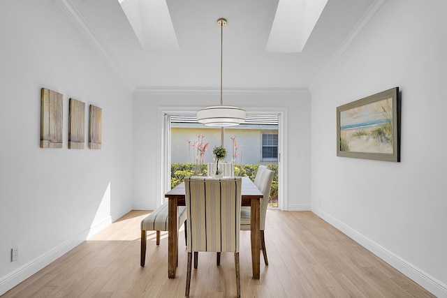 dining area with a skylight, crown molding, and light hardwood / wood-style floors