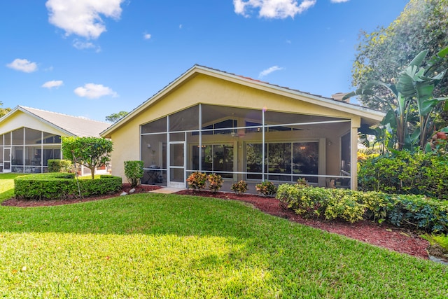 rear view of house featuring a sunroom and a yard