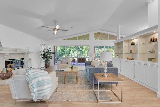 living room featuring ceiling fan, lofted ceiling, light wood-type flooring, and a high end fireplace