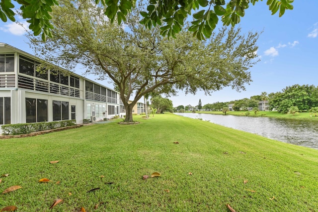 view of yard featuring a sunroom and a water view