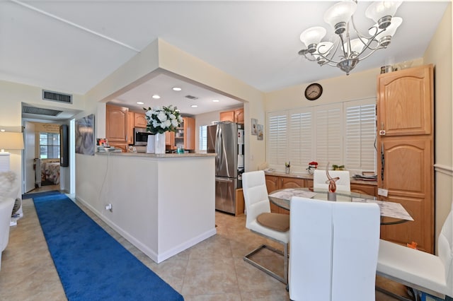 kitchen featuring stainless steel fridge, light tile patterned floors, kitchen peninsula, a breakfast bar, and an inviting chandelier