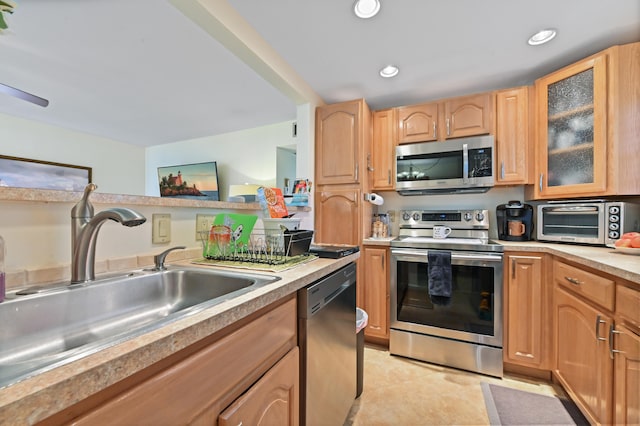 kitchen with light brown cabinetry, light tile patterned flooring, stainless steel appliances, and sink