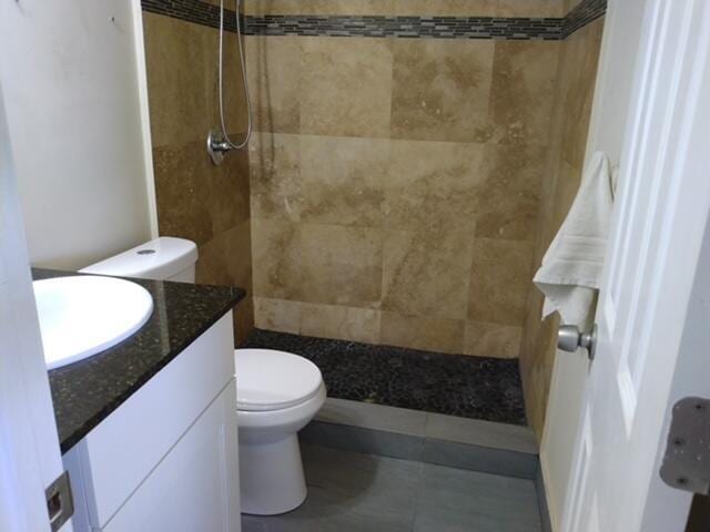 814 W Ocean Dr, Boynton Beach, FL 33426 - full bathroom with toilet, vanity, a tile shower, and tile patterned flooring