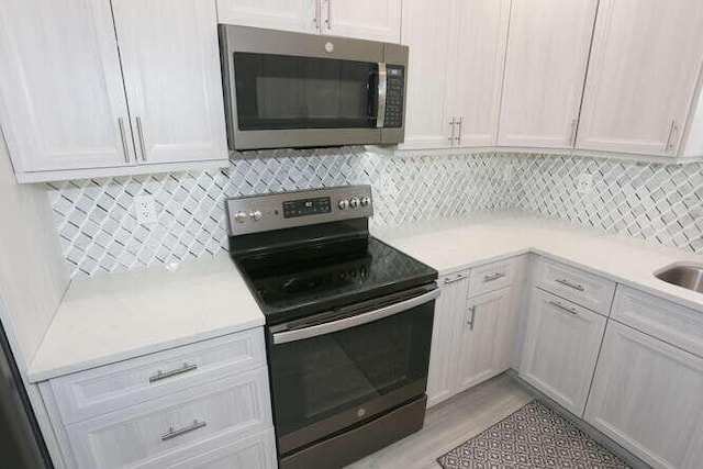 kitchen with decorative backsplash, stainless steel appliances, and white cabinets