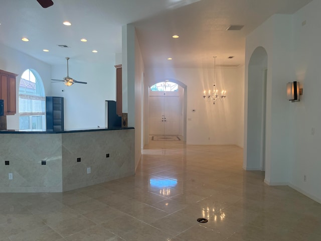 foyer entrance featuring tile walls, light tile patterned flooring, and ceiling fan with notable chandelier