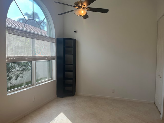 empty room with ceiling fan, light tile patterned flooring, and a wealth of natural light