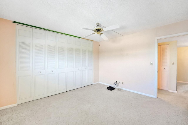 unfurnished bedroom with a textured ceiling, ceiling fan, light colored carpet, and a closet