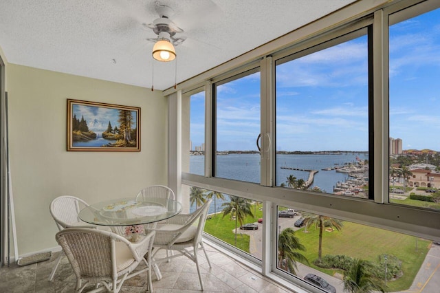 sunroom featuring ceiling fan and a water view