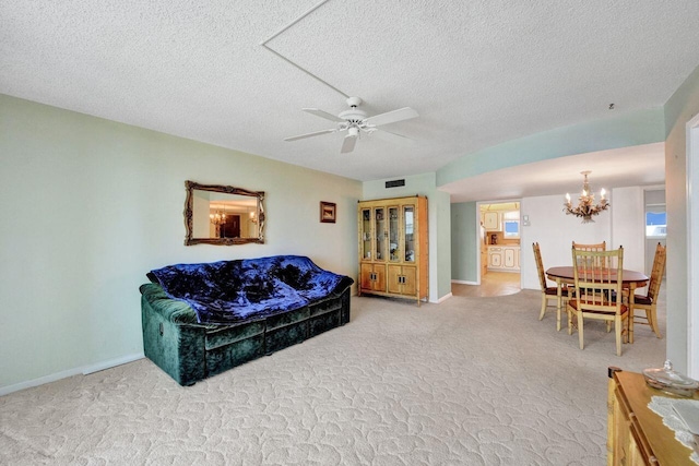 carpeted living room with a textured ceiling and ceiling fan with notable chandelier