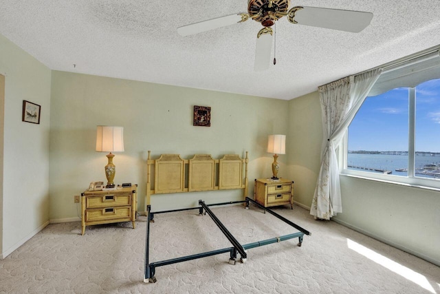 interior space featuring ceiling fan, a textured ceiling, and a water view