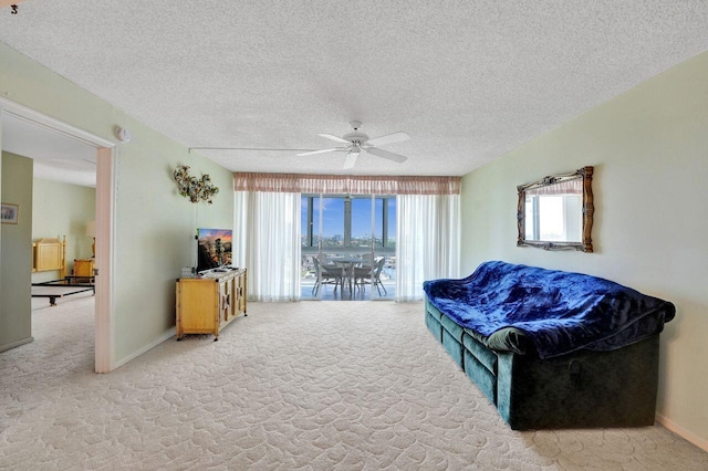 living area featuring ceiling fan, light colored carpet, and a textured ceiling