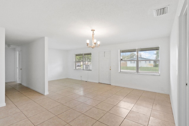 empty room featuring an inviting chandelier and light tile patterned floors