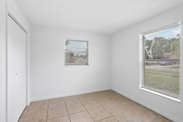 unfurnished bedroom featuring a closet, light tile patterned floors, and a textured ceiling