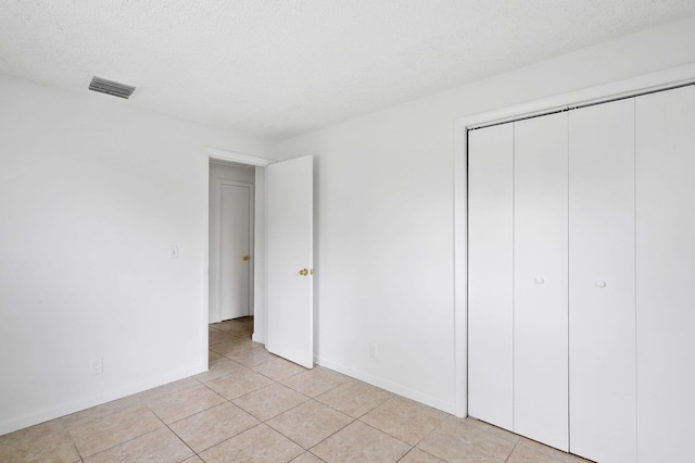 unfurnished bedroom with a textured ceiling, a closet, and light tile patterned floors