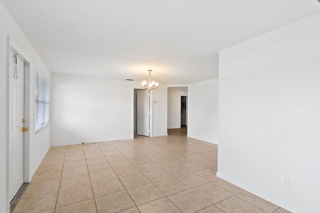 empty room featuring light tile patterned flooring and a chandelier