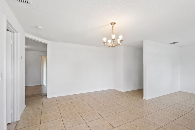 tiled empty room featuring a chandelier