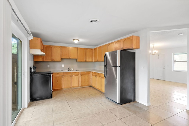 kitchen with light brown cabinets, stainless steel refrigerator, plenty of natural light, and electric range