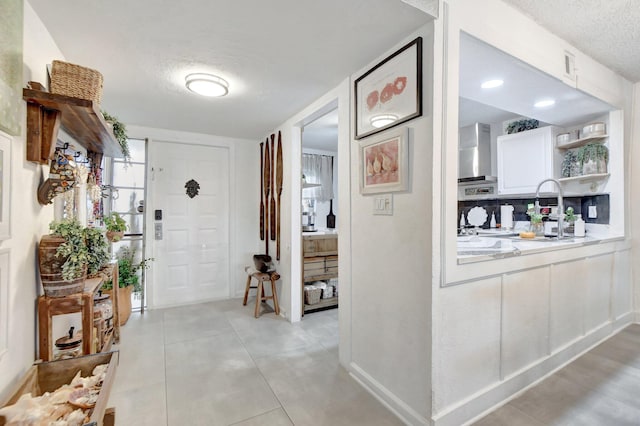 foyer entrance with a textured ceiling and light tile patterned floors