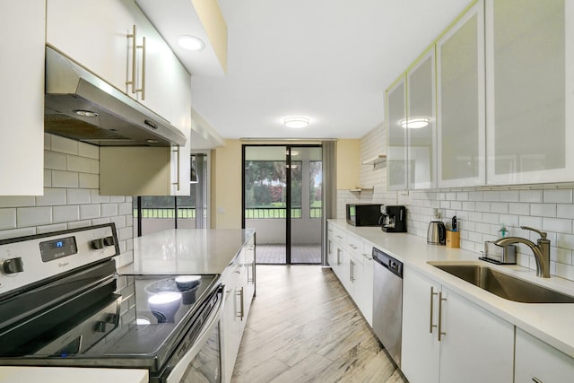 kitchen featuring sink, tasteful backsplash, white cabinetry, appliances with stainless steel finishes, and light hardwood / wood-style floors