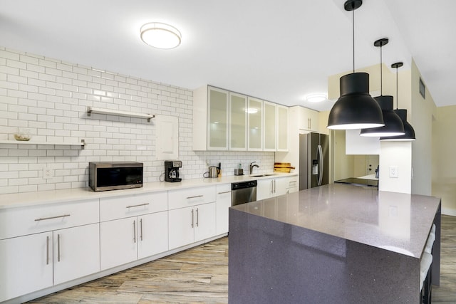 kitchen with pendant lighting, light hardwood / wood-style floors, white cabinetry, backsplash, and appliances with stainless steel finishes