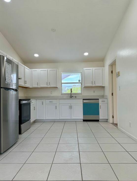 kitchen featuring light tile patterned flooring, white cabinetry, sink, and stainless steel appliances