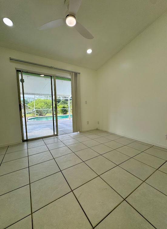 unfurnished room with vaulted ceiling, ceiling fan, and light tile patterned floors