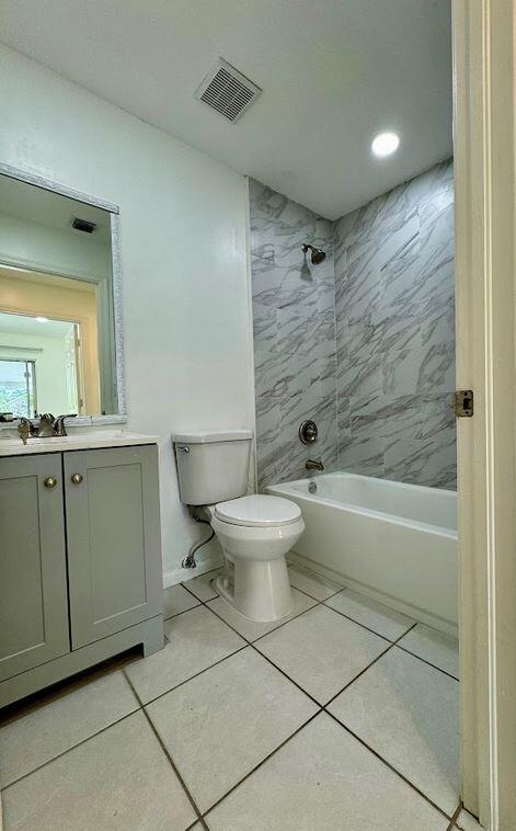 full bathroom featuring tiled shower / bath combo, vanity, toilet, and tile patterned floors