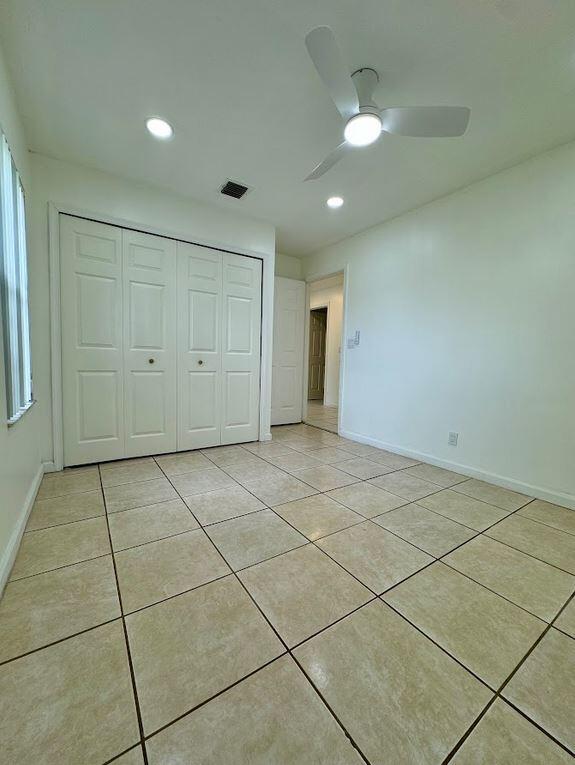 unfurnished bedroom with a closet, ceiling fan, and light tile patterned floors