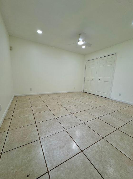 tiled spare room with ceiling fan