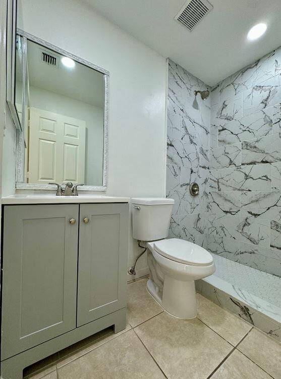 bathroom featuring vanity, tile patterned floors, toilet, and tiled shower