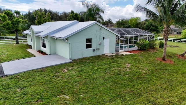 rear view of property featuring a patio, a swimming pool, a yard, and a lanai