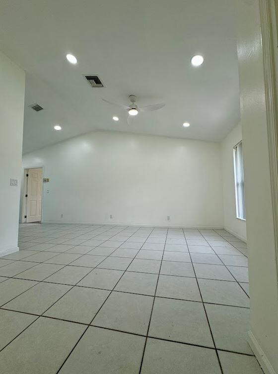 tiled spare room with lofted ceiling and ceiling fan