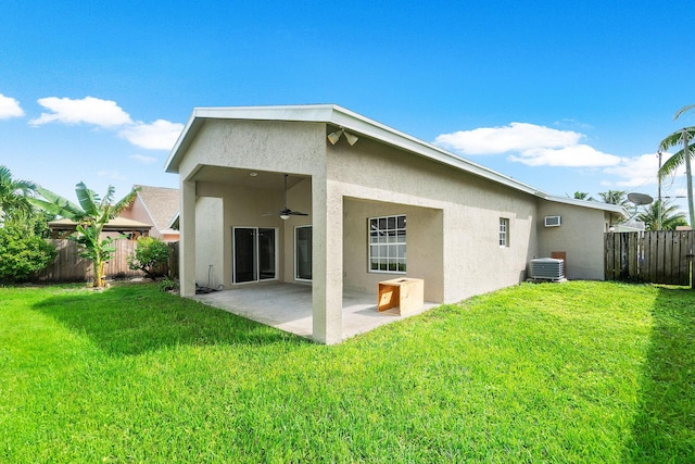 rear view of property featuring ceiling fan, a yard, a patio, and central AC