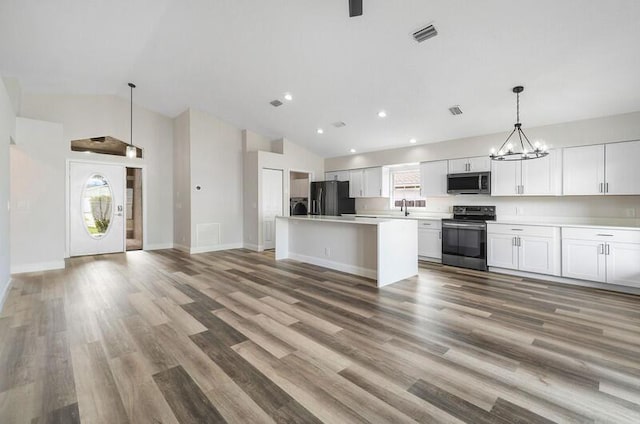 kitchen with appliances with stainless steel finishes, wood-type flooring, white cabinets, a center island, and hanging light fixtures