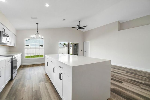 kitchen featuring appliances with stainless steel finishes, white cabinets, a kitchen island, hanging light fixtures, and lofted ceiling