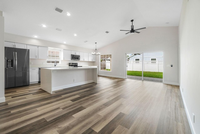 kitchen featuring ceiling fan with notable chandelier, a kitchen island, white cabinetry, and stainless steel appliances