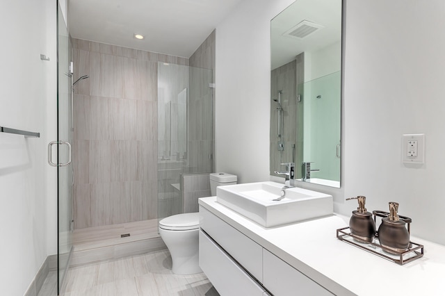 bathroom with a shower with door, vanity, and toilet