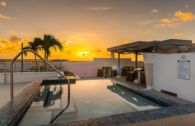 pool at dusk featuring a patio