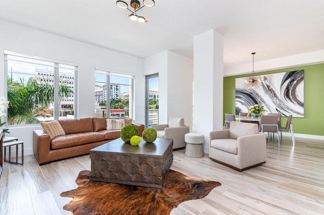 living room with light hardwood / wood-style flooring, plenty of natural light, and an inviting chandelier